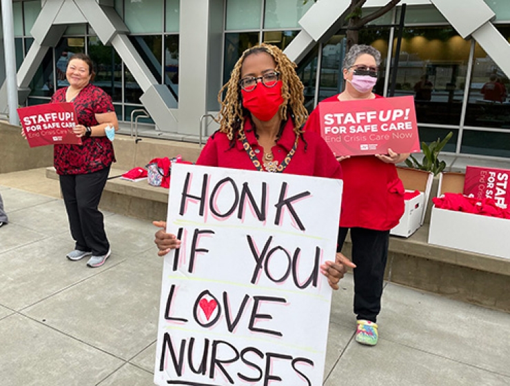Nurse outside hospital holds sign "Honk if you like nurses"